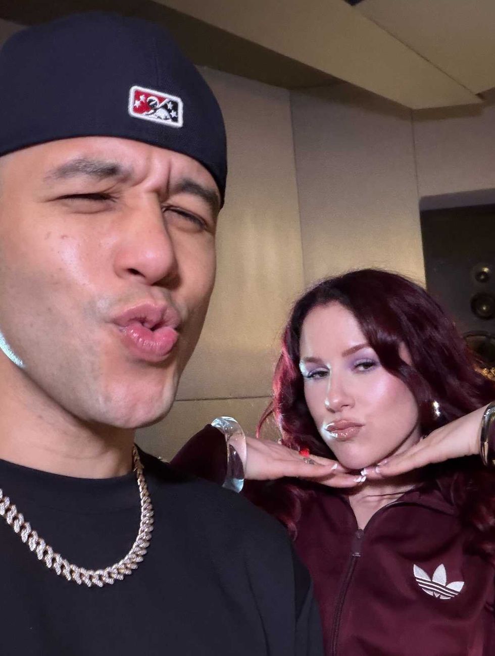 Katy B & Jax Jones pose playfully, both making pouting faces in a dimly lit room.