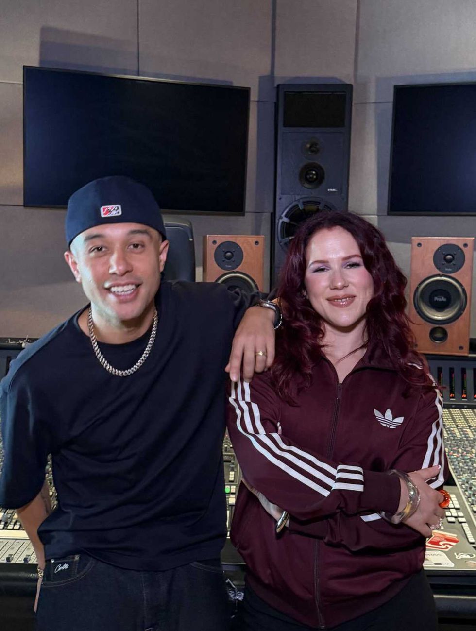 Katy B & Jax Jones smiling in a music studio with audio equipment in the background.