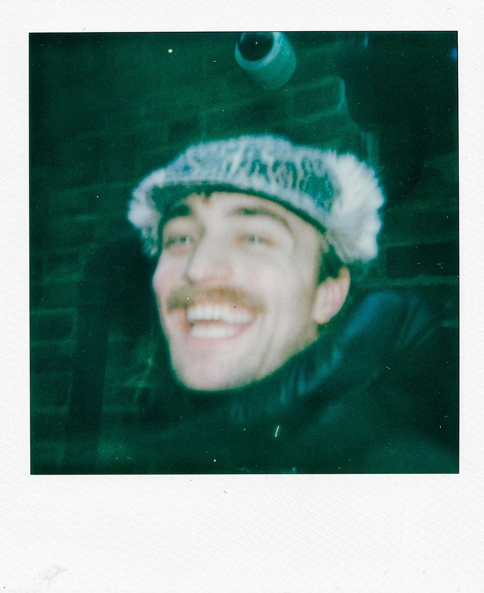 Smiling Martin Luke Brown with a furry hat and a mustache in a vintage-style photo.