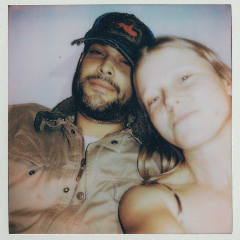 strongboi posing closely for a vintage Polaroid photo, one wearing a cap.